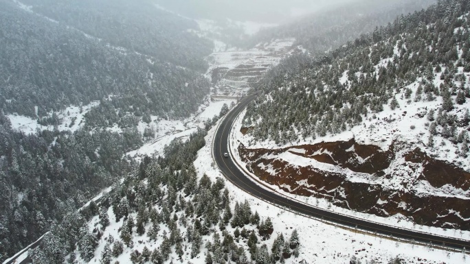 4K航拍雪天白色汽车行驶在高原雪山公路