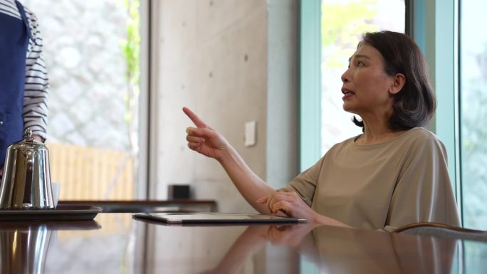 小企业主-顾客坐在餐厅的桌子上，对员工生气