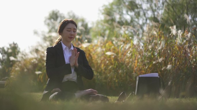 瑜伽在城市-年轻女子在草地上冥想