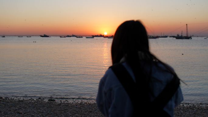 海边一名女子在夕阳下孤独的等待