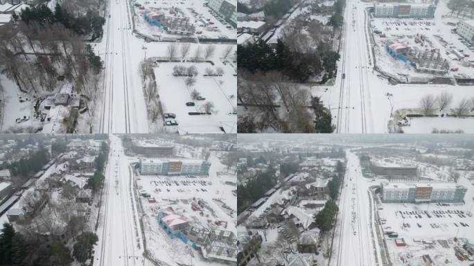 无人机镜头展示了一条被雪覆盖的道路，路上有经过的汽车，镜头向上升起，进入一条延伸的多云道路。