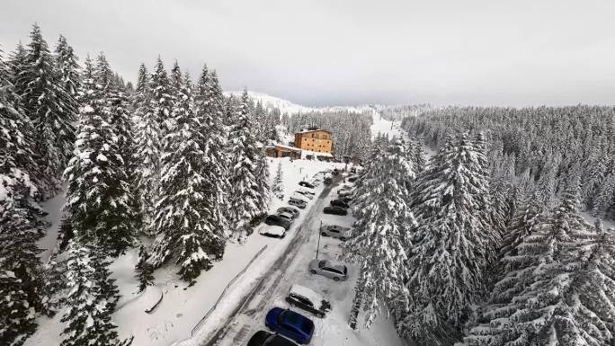 冬季山路上覆盖着雪的汽车的鸟瞰图，通往一家酒店。