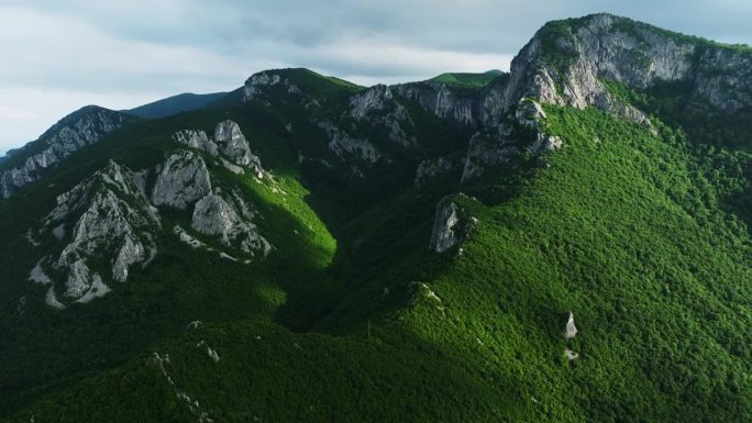 广阔的山脉在阴云密布的雨天中被阳光照亮，清新的空气，乡村航拍升起。