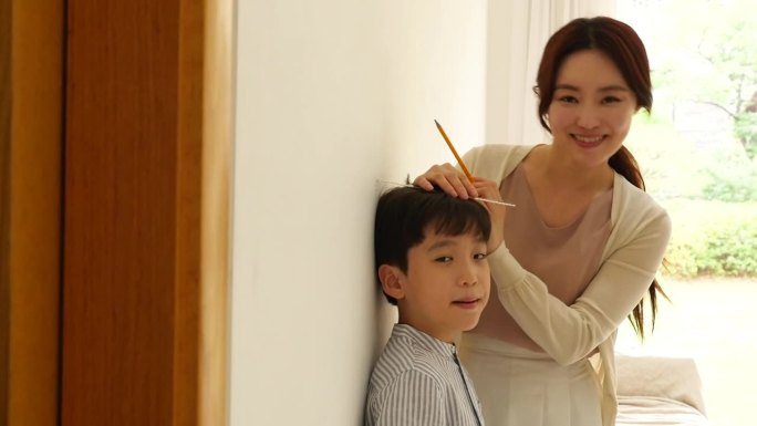 母亲在客厅给儿子量身高