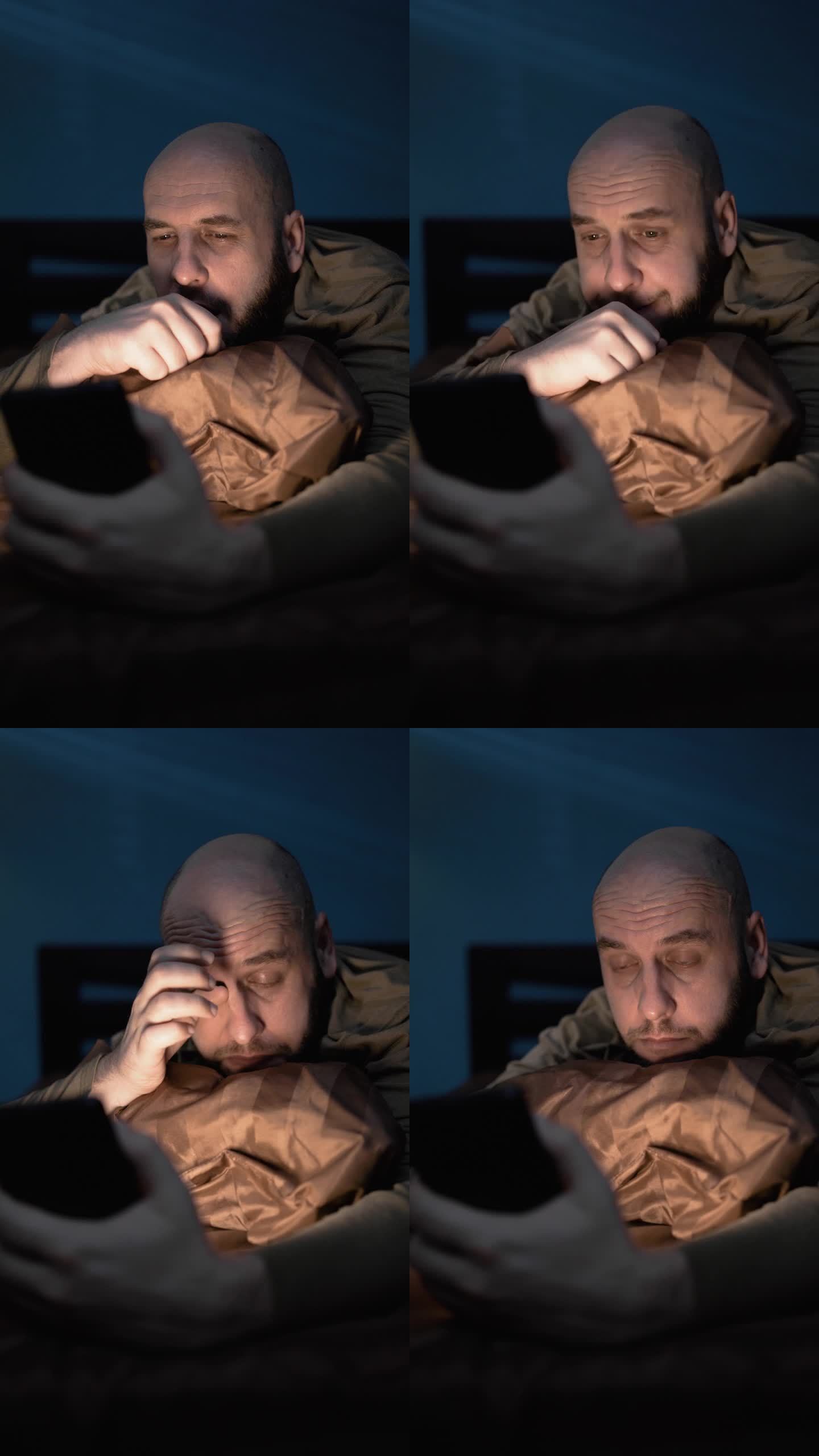 疲惫困倦的男人躺在床上,深夜使用智能手机,无法入睡.失眠和睡眠障碍