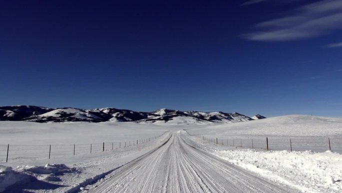 盘山上下POV的雪道上，以雪山为背景的草原景观。