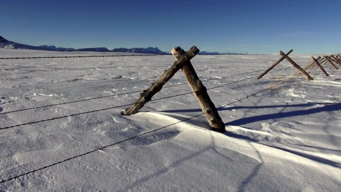 潘离开POV的铁丝网，在雪堆上覆盖着草原景观，背景是群山。