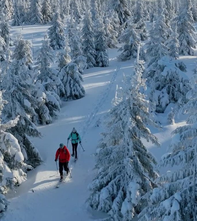 冬季山脉上，穿着雪鞋的滑雪旅行男女的航拍视角。