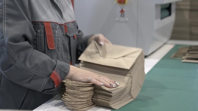 工厂员工检查堆叠纸购物袋的质量。