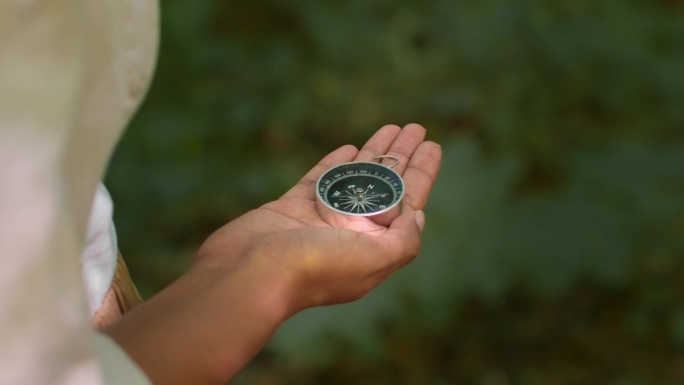 女性手中指南针的特写，不可辨认的女游客在森林中寻找北方，慢动作，空旷的空间。