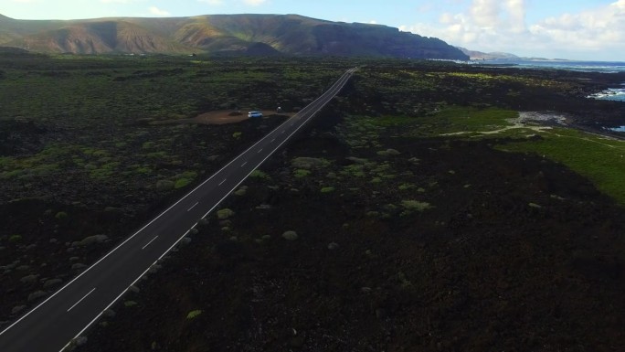 无人机在美丽的兰萨罗特火山岛北部海岸上空拍摄的航拍画面，海岸线上有一条笔直的长路，令人惊叹。4 k 