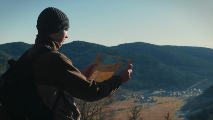 登山者来到山顶，手里拿着地图，寻找方向。
