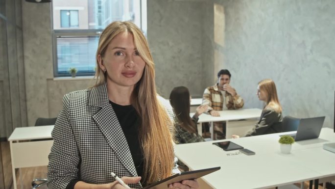 一位年轻的老师穿着正式的夹克，正在准备在一群大学生面前开始她的讲座。