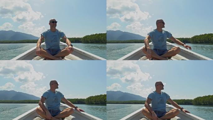 成年男子坐在船头，享受新鲜空气，享受生活，欣赏这次美妙旅行的美景。