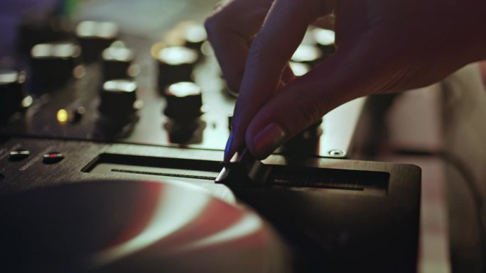 手在夜总会特写调整DJ设备的滑块。未知的DJ。