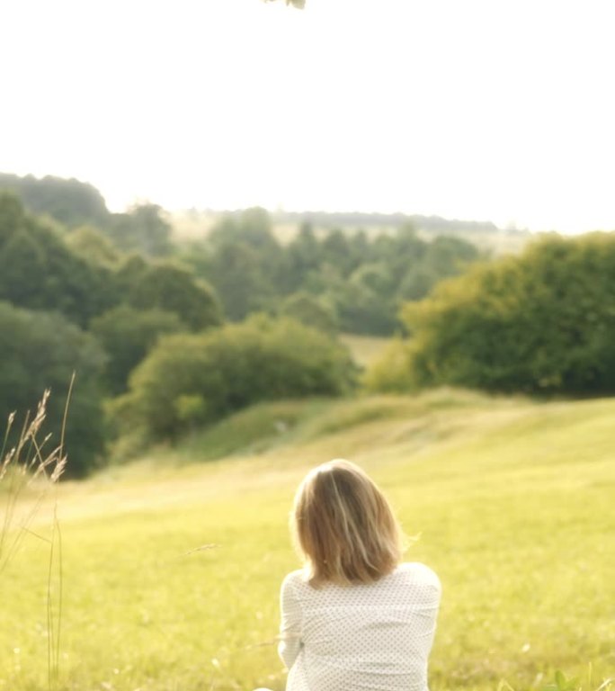 宁静的草地度假：中年女性在孤独的树下放松。