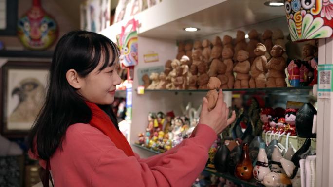 女孩欣赏购买非遗文创产品泥人张
