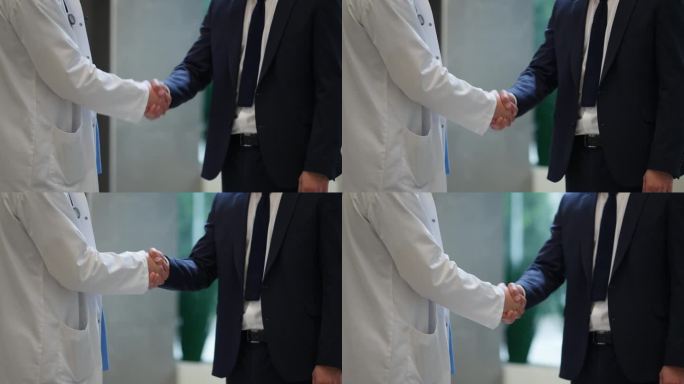医生与身穿西装的专业人士握手的特写，象征着在专业医疗环境中的合作与信任。合作伙伴关系和相互尊重的概念