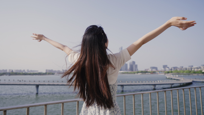 女人湖边城市风光下的休闲时光春天温暖阳光