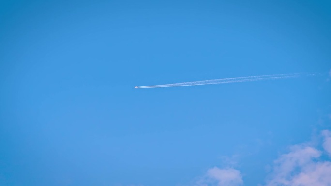 飞机在蓝天高空飞行，留下白色的航迹。飞机在清澈的空气中翱翔，拖着凝结的水汽。喷气机穿越开阔的天空，形