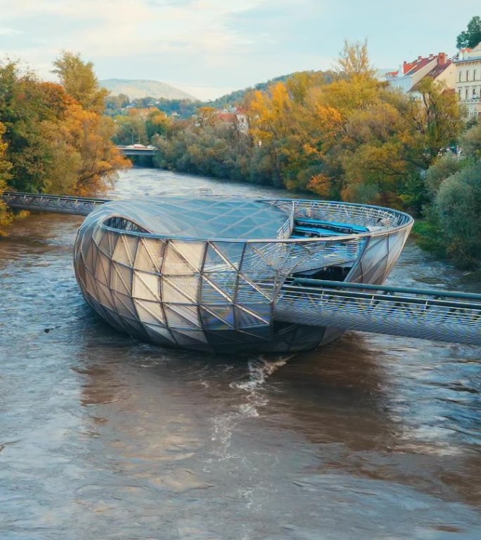 穆尔岛：漂浮在穆尔河上的人工岛，四周被格拉茨的秋季树木环绕。
