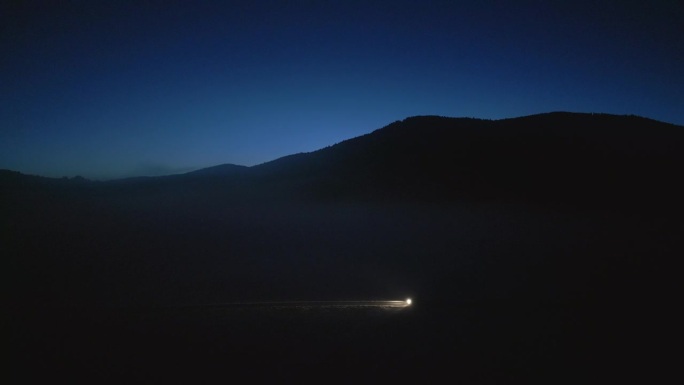 车灯照亮的公路旁，山脉剪影的侧面镜头。