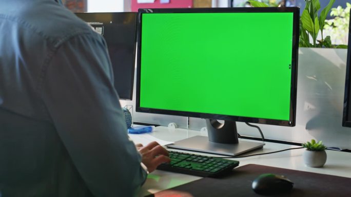 未知自由职业者在现代工作场所近距离使用绿幕电脑。