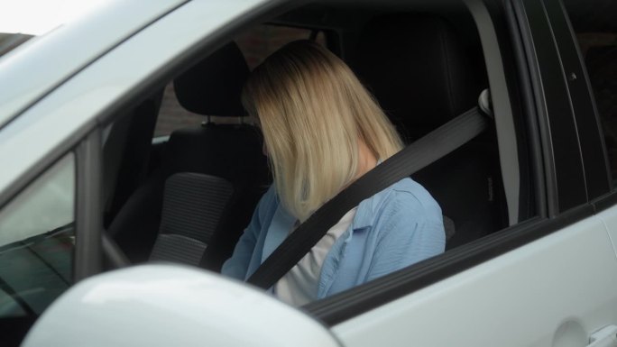 白人女商人坐在车里系好安全带，微笑着驾驶新购的汽车，进行城市试驾，享受安全旅行的服务。