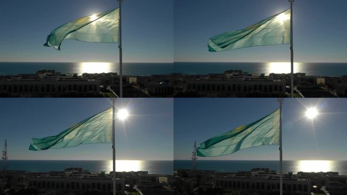 AKTAU, 哈萨克斯坦 - 2025年2月1日：阳光照耀在城市天际线和闪烁的里海上，绿色旗帜在明亮