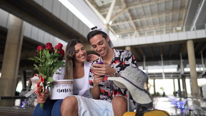 年轻情侣在机场使用手机。