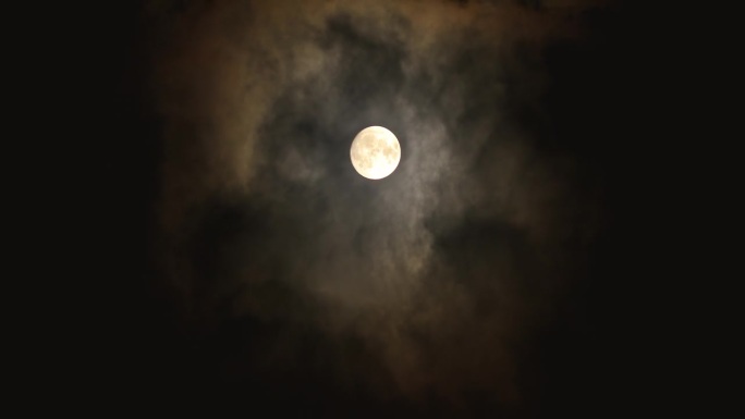 满月在夜空中透过黑暗的云层闪耀。