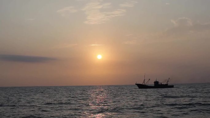 夕阳下渔船在大海上行驶