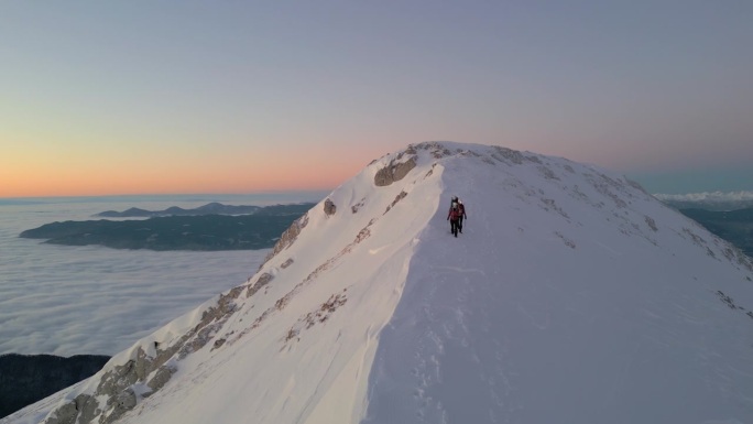 日落时分的山顶徒步旅行，雪峰与云彩，冒险者们。