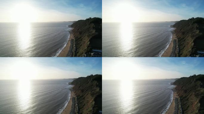 从空中俯瞰阳光在英吉利海峡平静水面上的倒影，前景是布兰斯科姆海滩及其悬崖。镜头向前推进。