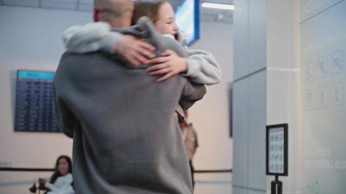 快乐的男人在机场候机厅迎接刚从旅行回来的家人。