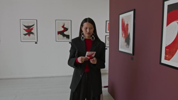 微笑的亚洲艺术展览参观者在画廊阅读宣传册的肖像。