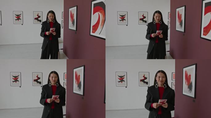 微笑的亚洲艺术展览参观者在画廊阅读宣传册的肖像。