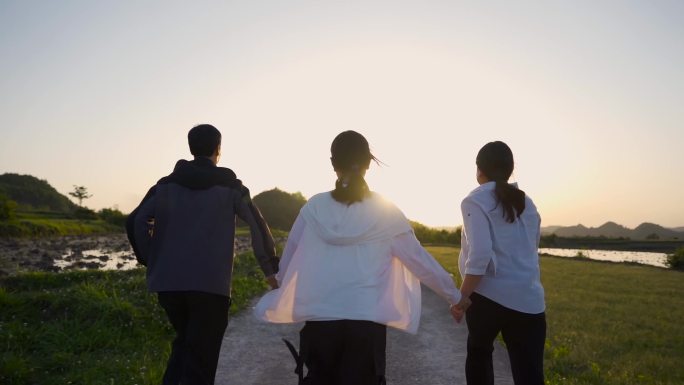 一家三口手牵手 夕阳下奔跑背影 道路