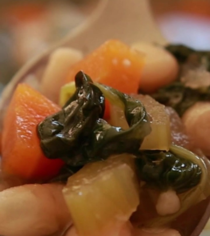 浓郁的意大利豆子菠菜汤在轻轻炖煮，顶部撒上新鲜磨碎的帕尔马干酪。