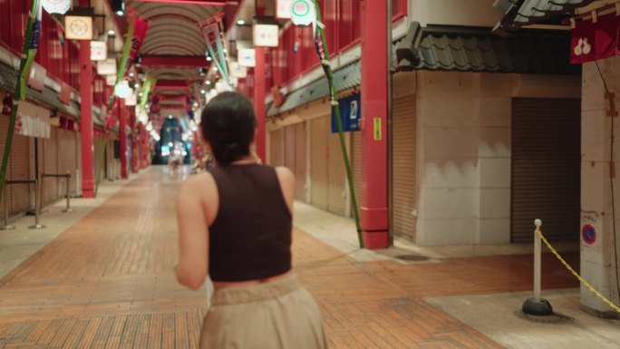 两个女性游客朋友在东京的历史传统购物街夜间互相拍照。