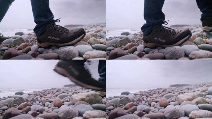 慢动作片段：哥伦比亚登山鞋在海浪旁的卵石海滩上。