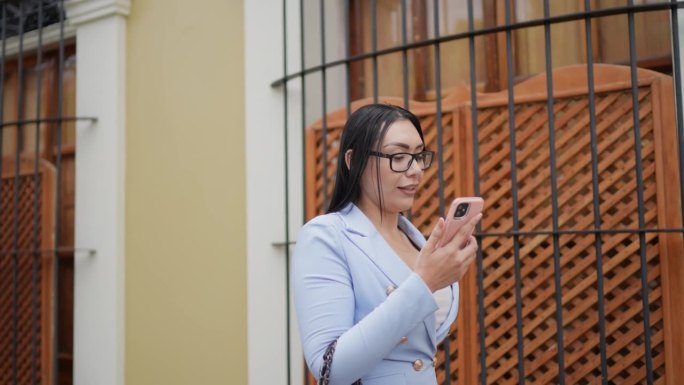 中年成年女商人在历史街区的户外用手机做视频通话
