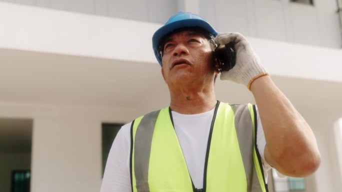成熟的蓝领建筑工人在打电话。