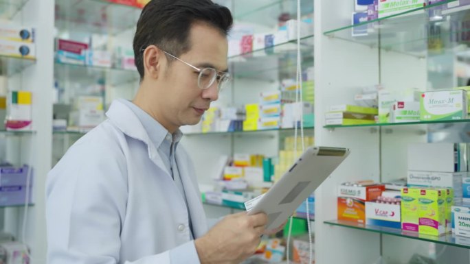 男药剂师在药店使用药片工作。
