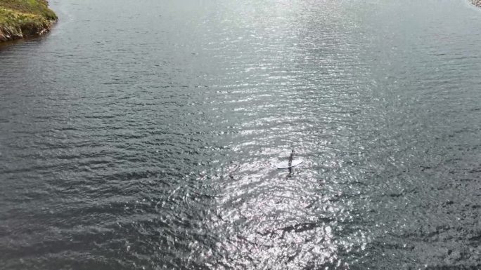 一名女子在一个大湖上享受划桨冲浪