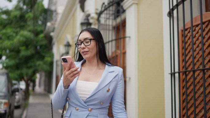 中年成年女商人在历史街区的户外用手机做视频通话