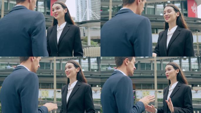 白人商人和女商人在城市的户外握手。有吸引力的员工团队站在办公室外洽谈业务，享受合作协议