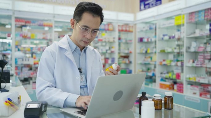 男药剂师使用笔记本电脑在药店工作。