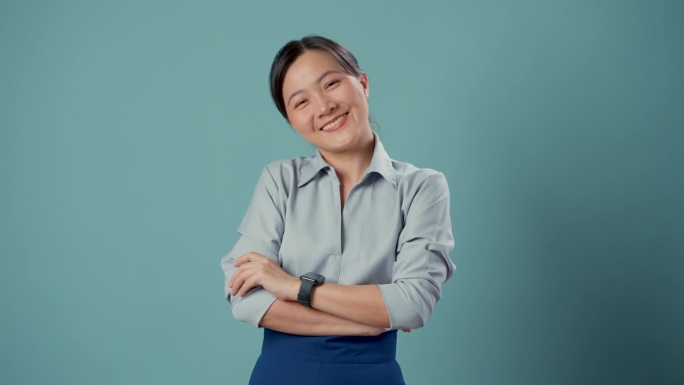 亚洲女人快乐自信地站在蓝色的背景隔离双臂。