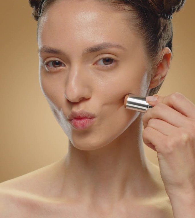 女人在脸上涂古铜色化妆品。